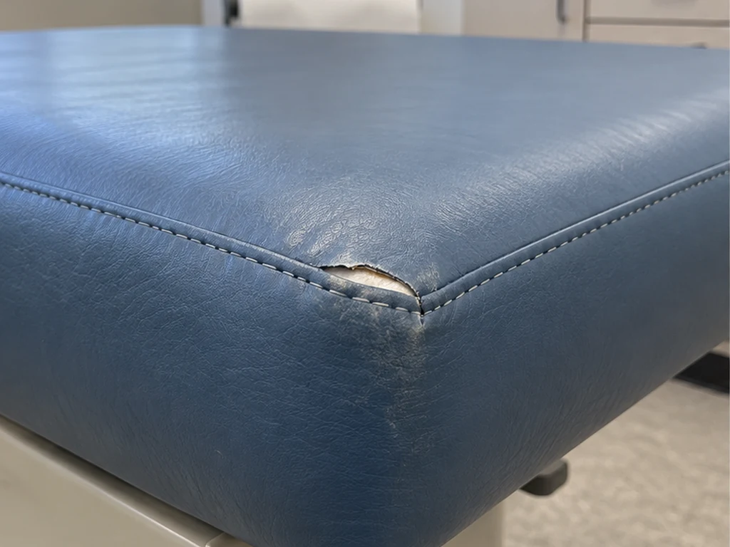Illustrative view of a blue medical exam table with a corner tear