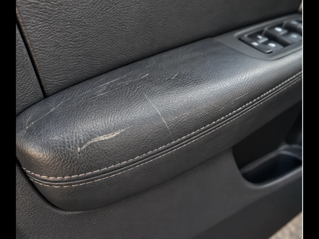 Illustrative view of a scratched black leather car door armrest